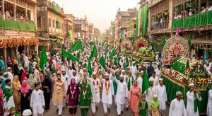 Muslims participating in Eid-e-Milad procession with green flags and banners celebrating Prophet Muhammad's birth anniversary