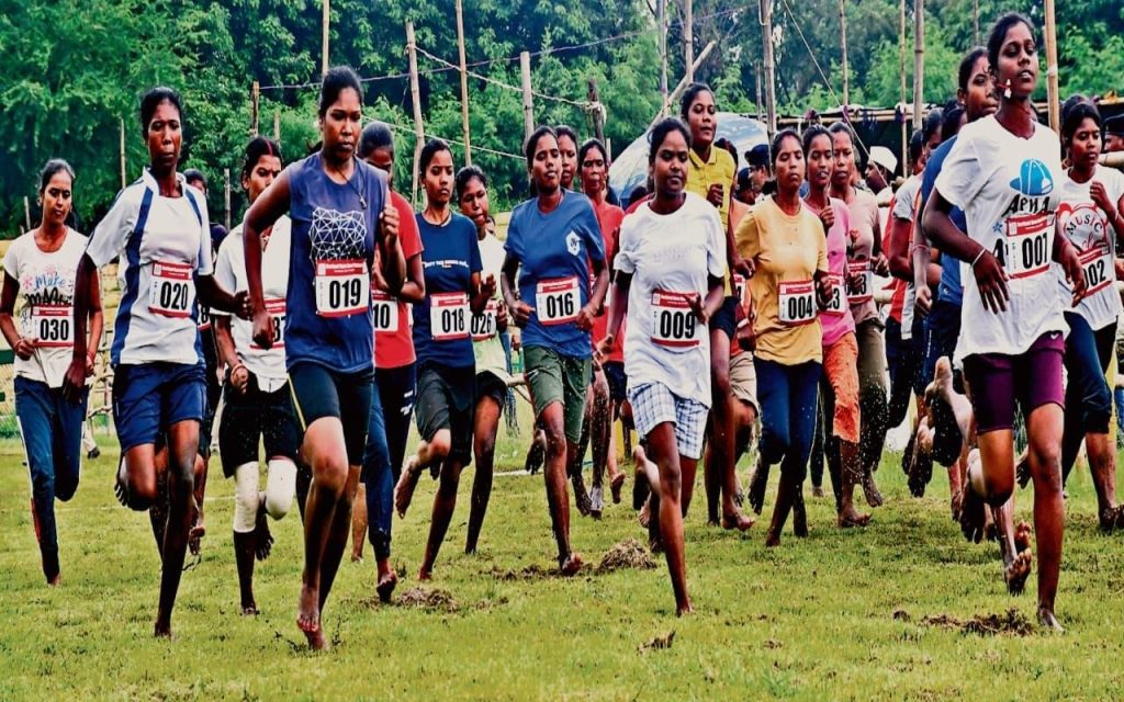 Women preparing for the Jharkhand Home Guard recruitment trial run at an outdoor stadium.